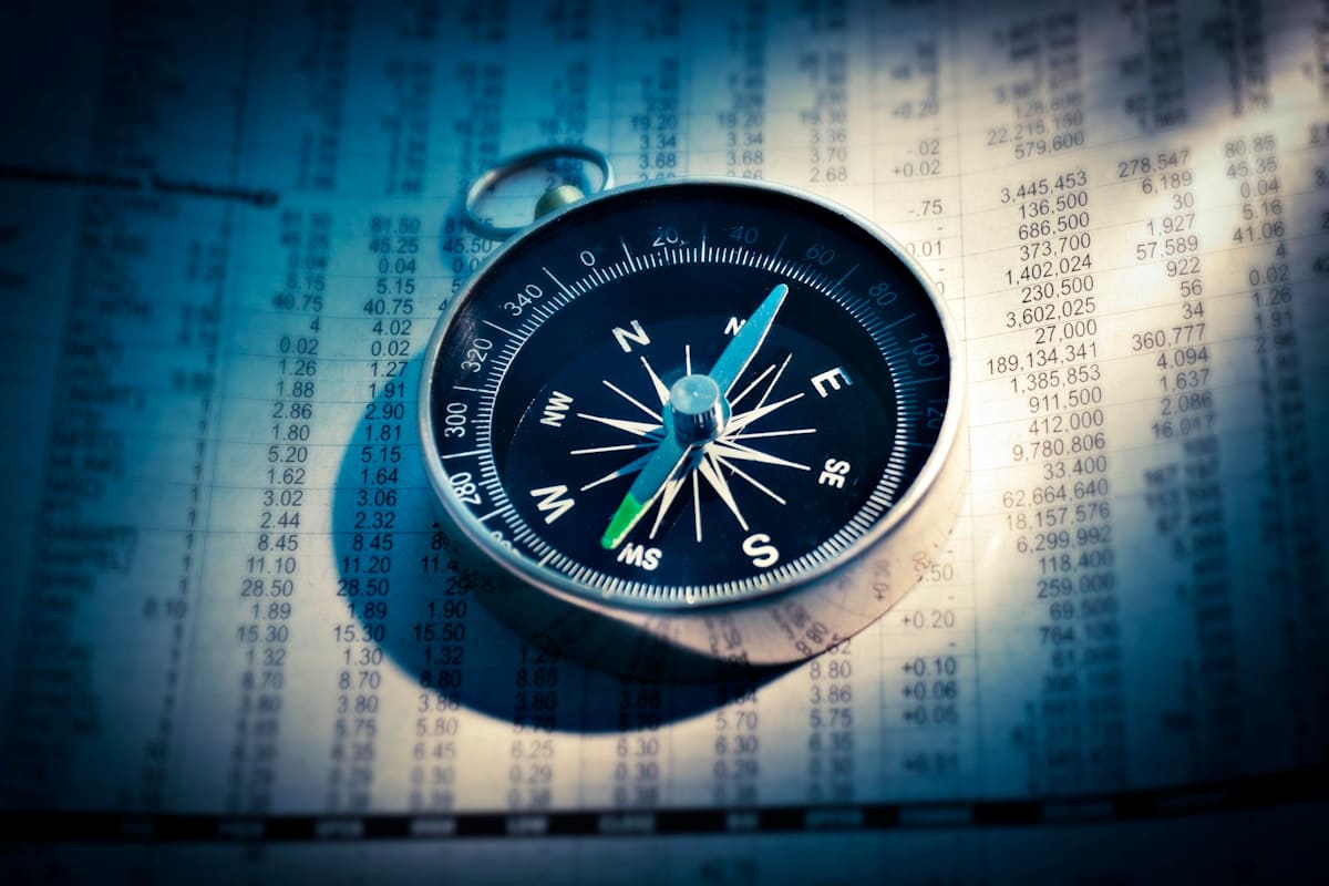 A magnetic compass resting on a page of navigation tables and figures